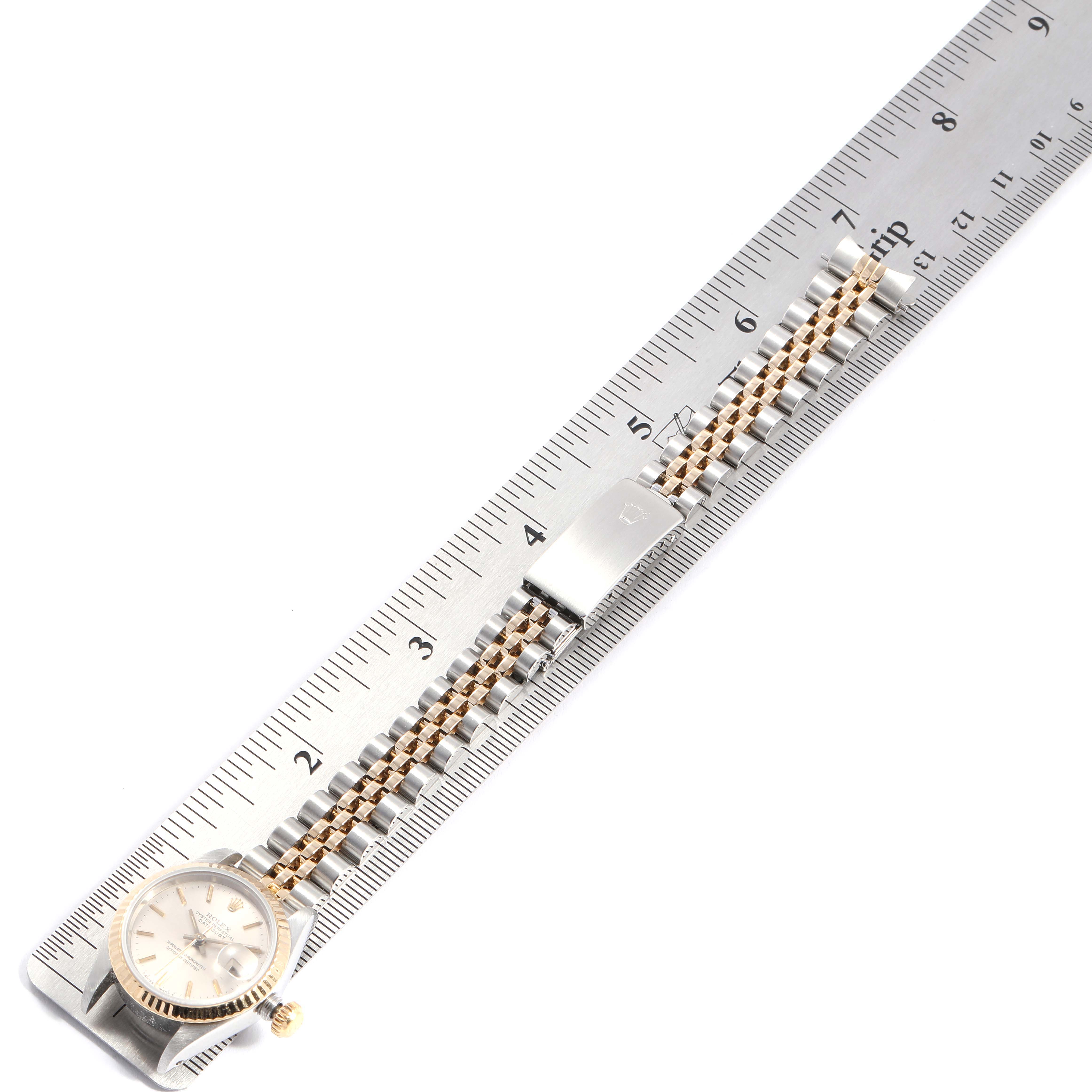 This image shows the Rolex Datejust 69173 Women
s Steel and Gold (two tone) Silver Dial 69173 Women
s Steel and Gold (two tone) Silver Dial watch from a top view, alongside a ruler for scale.