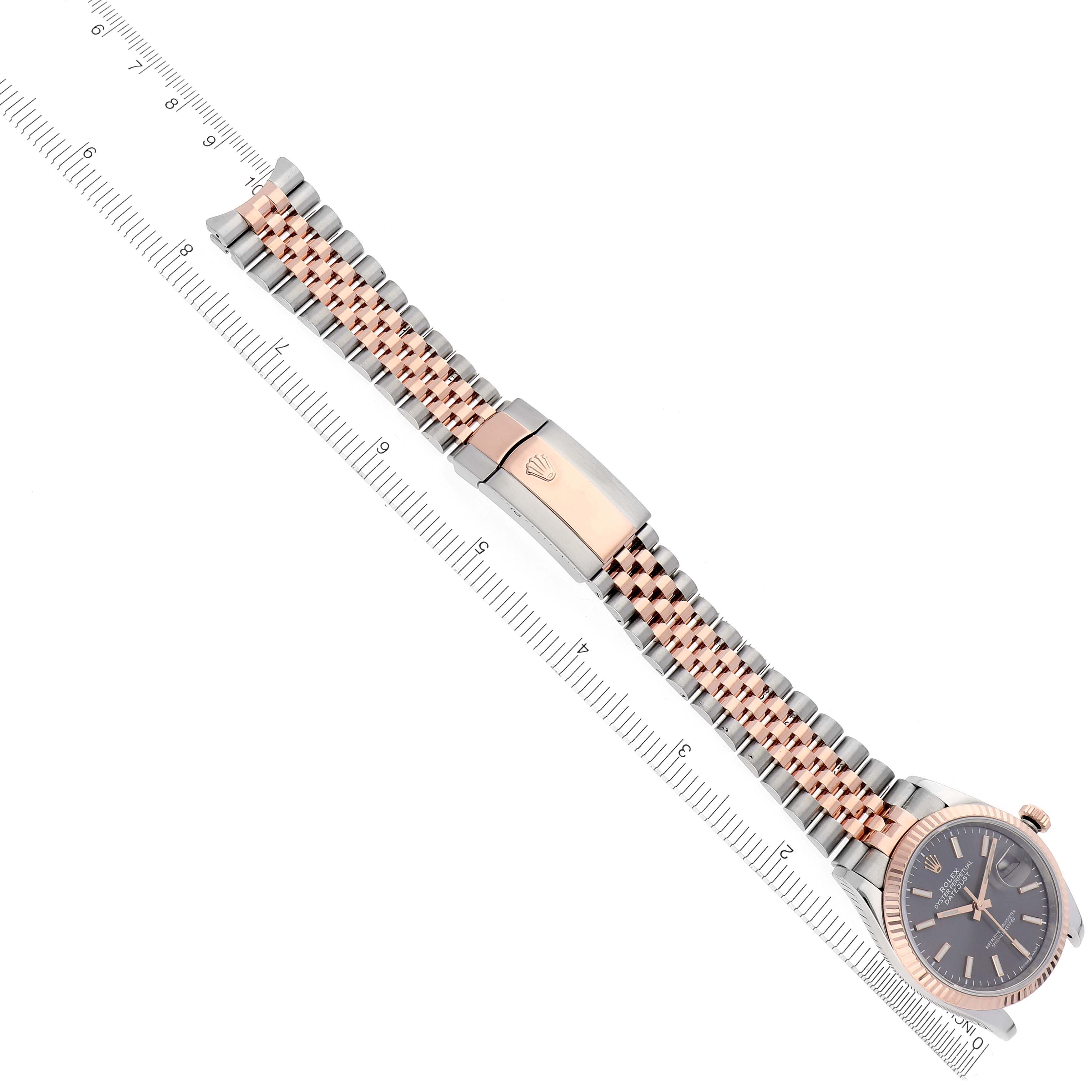 The Rolex Datejust 126231 Men's Steel and Gold (two tone) Grey Dial 126231 Men's Steel and Gold (two tone) Grey Dial watch is shown from a top view, highlighting its bracelet and clasp, alongside a measuring ruler.