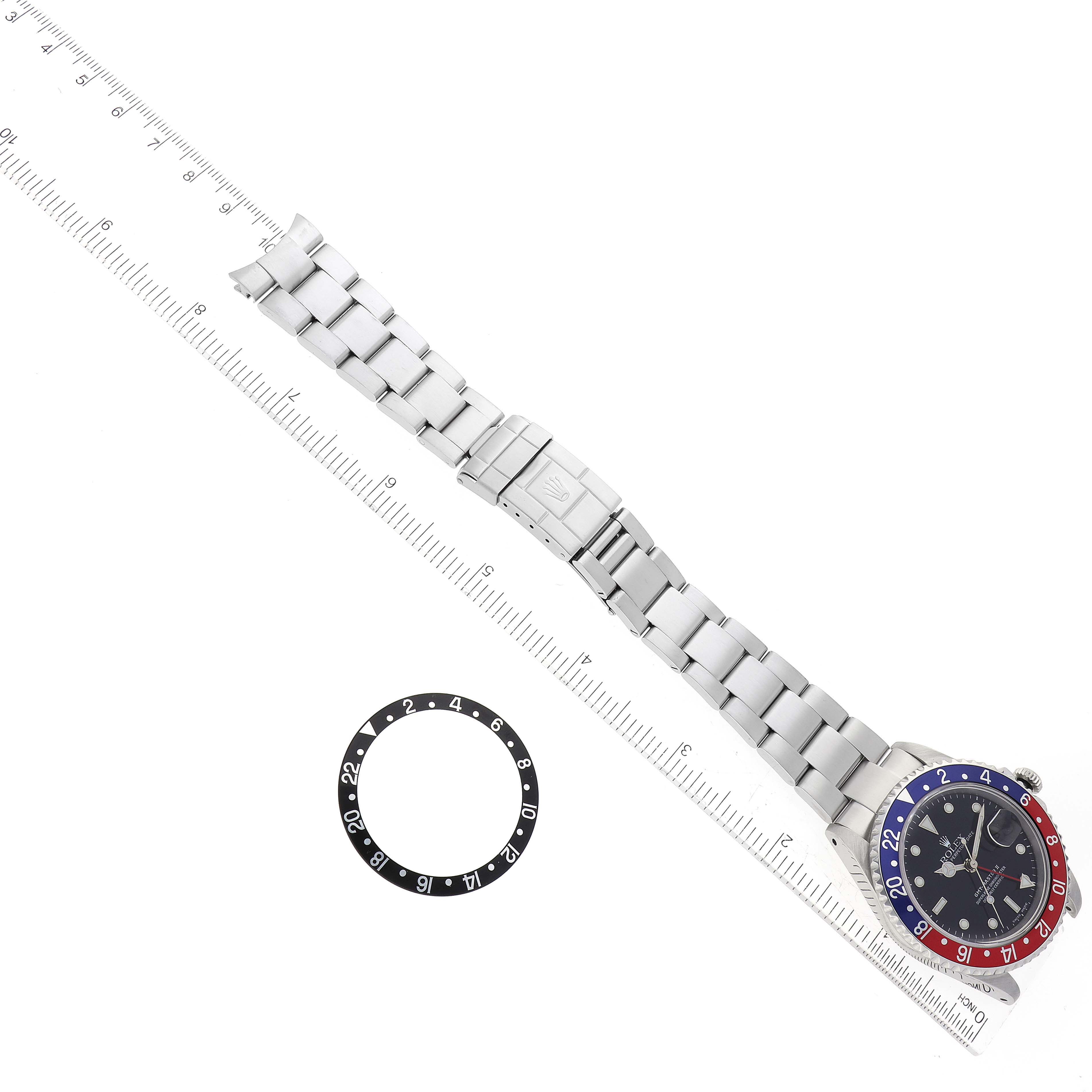 The image shows a Rolex GMT-Master 16710 Men's Stainless Steel Black Dial 16710 Men's Stainless Steel Black Dial watch laid flat with a separate bezel insert and a ruler for scale.