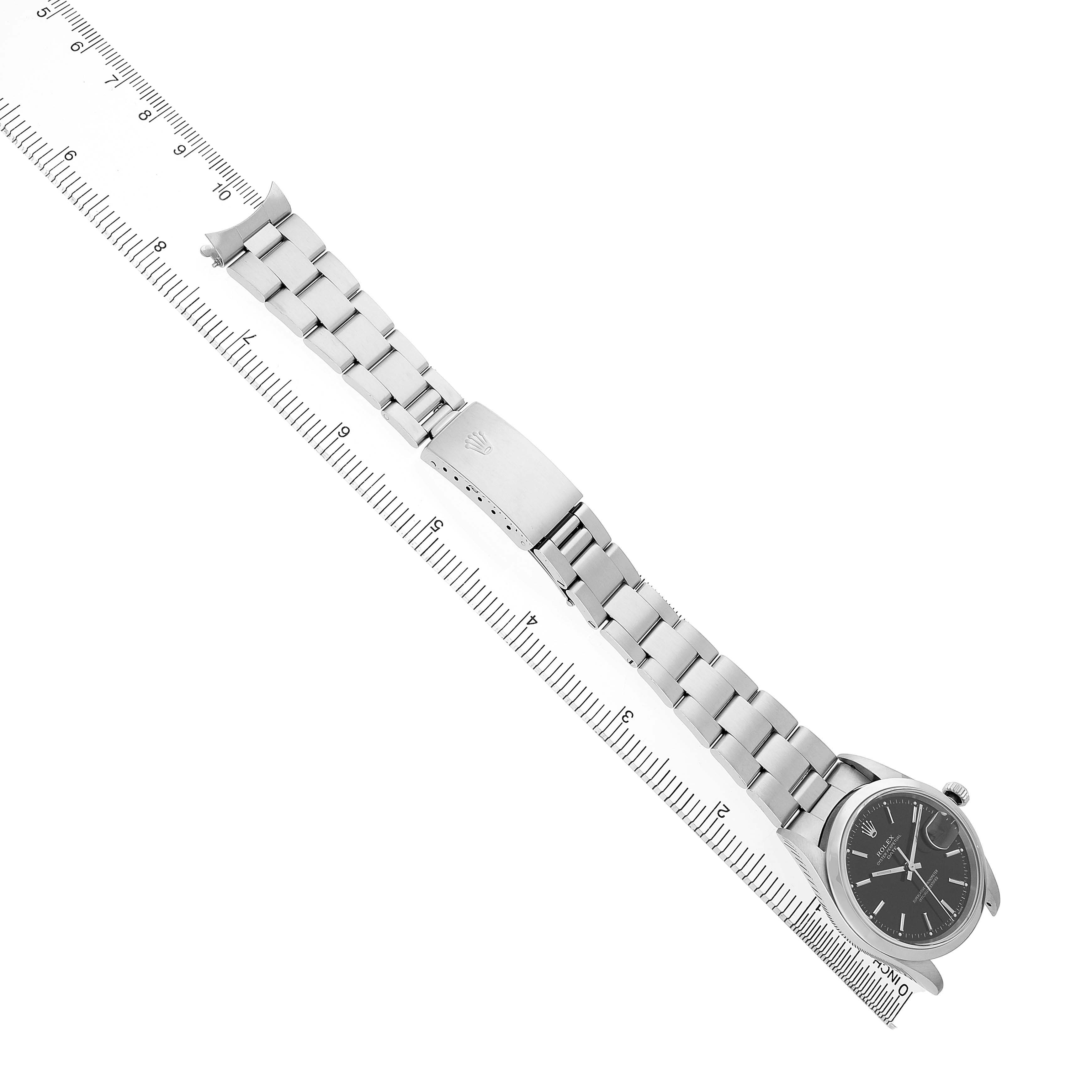 The Rolex Oyster Perpetual 15200 Men's Stainless Steel Black Dial watch is shown from a top view, displaying the full bracelet and dial, with a ruler alongside for scale.