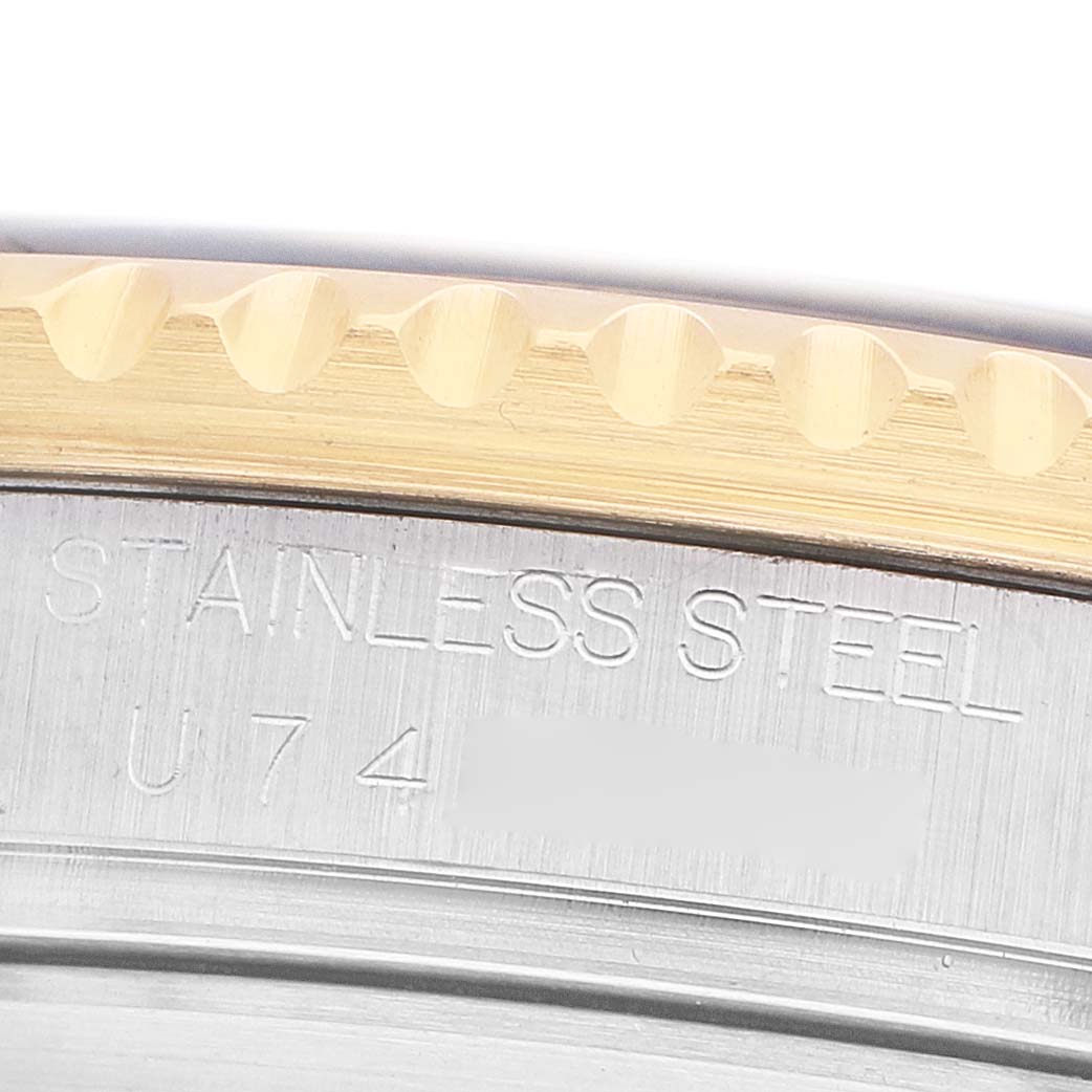 The image shows a close-up of the edge of a Rolex Submariner 16613 Men's Steel and Gold (two tone) Blue Dial bezel and casing, highlighting the "STAINLESS STEEL" engraving.