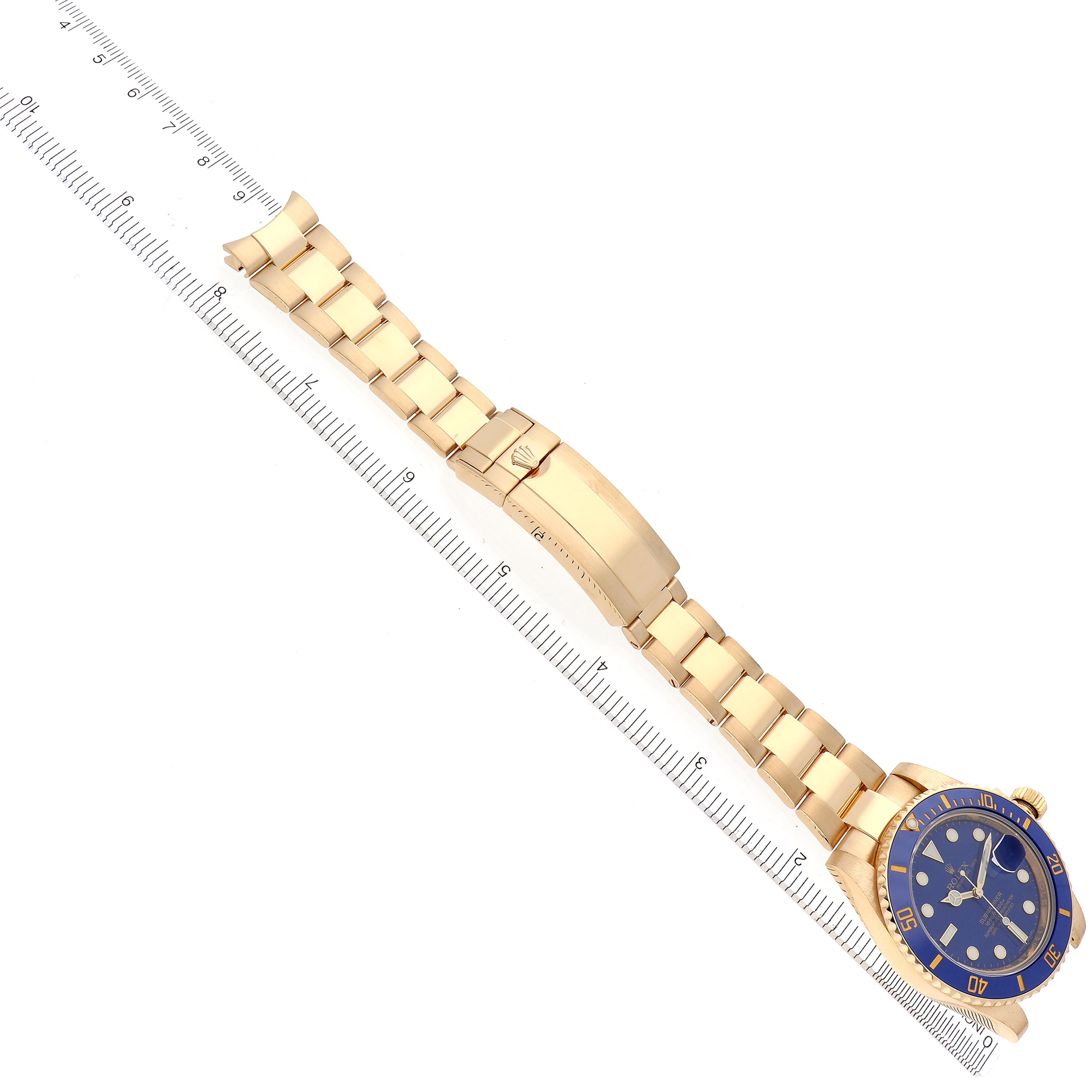 The image shows a Rolex Submariner 116618LB Men's Yellow Gold Blue Dial 116618LB Men's Yellow Gold Blue Dial watch laid flat with its bracelet extended next to a ruler.