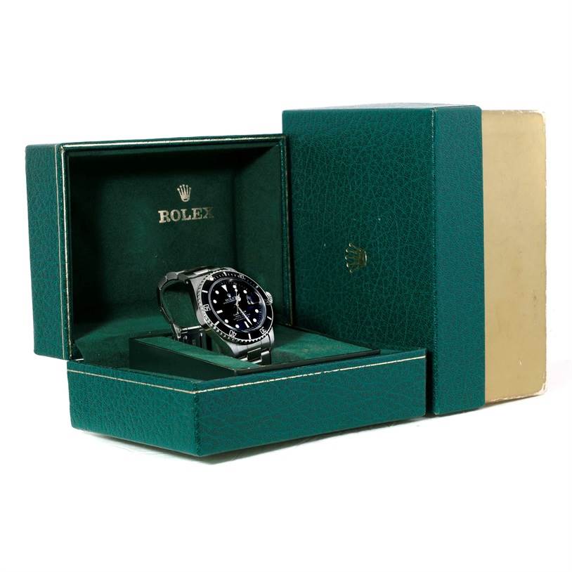 This image shows a Rolex Submariner 168000 Men
s Stainless Steel Black Dial 168000 Men
s Stainless Steel Black Dial watch angled inside its open green packaging box.