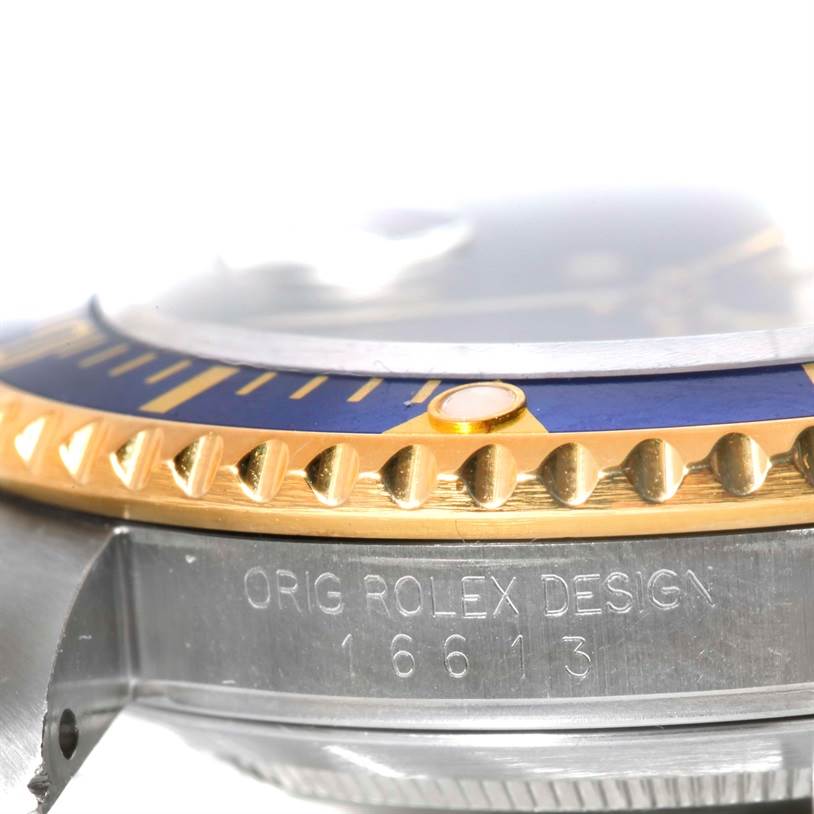 The image shows a close-up, side-angle of the Rolex Submariner 16613 Men's Steel and Gold (two tone) Blue Dial 16613 Men's Steel and Gold (two tone) Blue Dial model, highlighting the bezel, crystal, and engraved case.