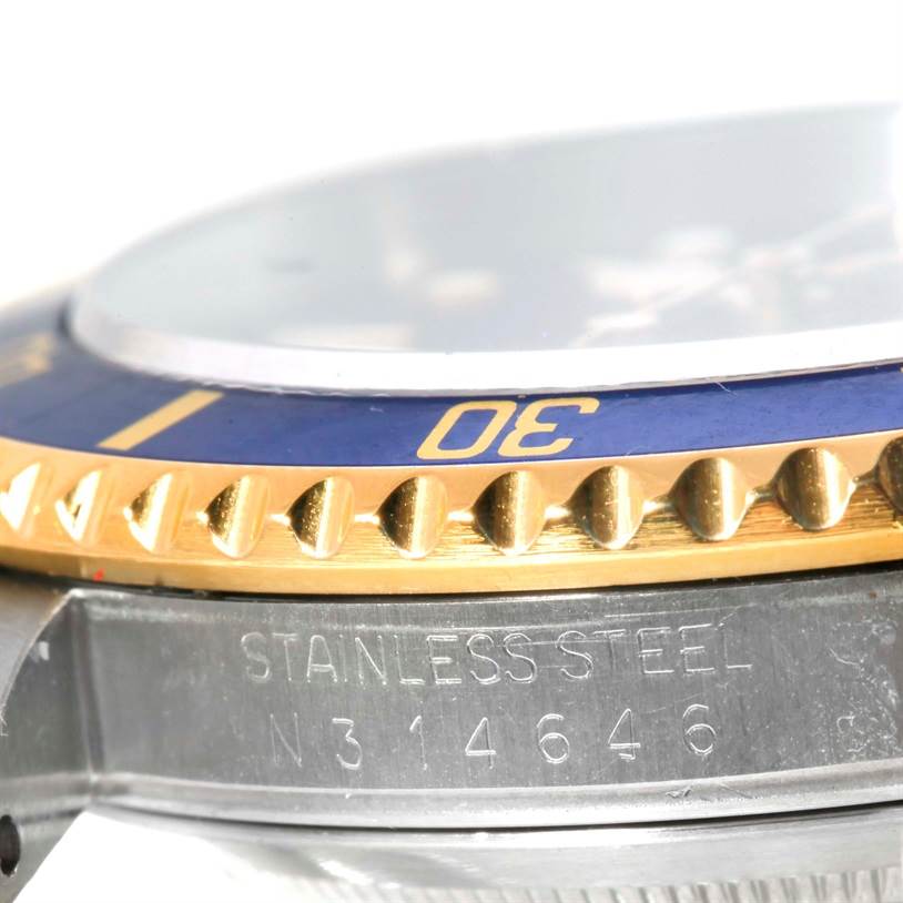 This close-up shot of the Rolex Submariner 16613 Men's Steel and Gold (two tone) Blue Dial 16613 Men's Steel and Gold (two tone) Blue Dial watch shows the stainless steel band, beze,l and part of the dial.