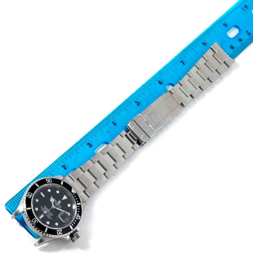 This image shows the full length of a Rolex Submariner 16610 Men
s Stainless Steel Black Dial 16610 Men
s Stainless Steel Black Dial watch and its bracelet laid flat next to a ruler for measurement.