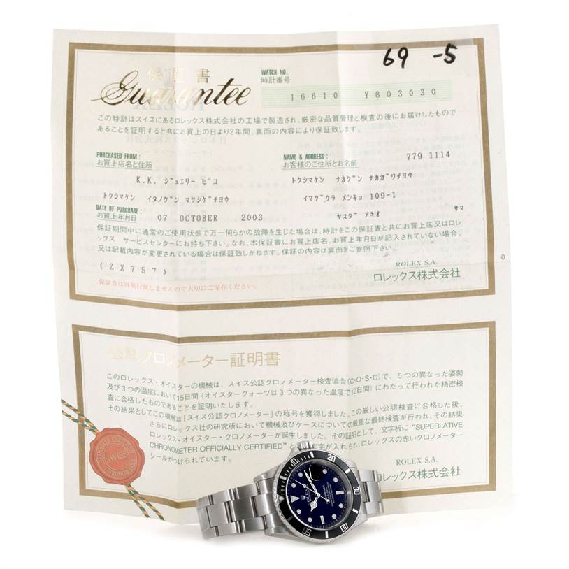 The image shows a Rolex Submariner 16610 Men
s Stainless Steel Black Dial 16610 Men
s Stainless Steel Black Dial watch displayed in front of its guarantee certificate, viewed from the front.