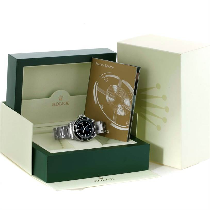 The image shows a Rolex Submariner 16610 Men
s Stainless Steel Black Dial 16610 Men
s Stainless Steel Black Dial model watch and its box, with the interior display and accompanying factory service booklet.