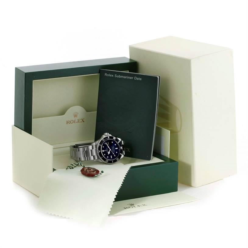 The image shows a Rolex Submariner 16610 Men
s Stainless Steel Black Dial 16610 Men
s Stainless Steel Black Dial watch with its box, manual, tags, and cleaning cloth.