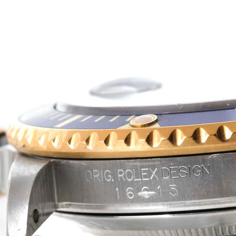 This close-up angle shows the side view of the Rolex Submariner 16613 Men
s Steel and Gold (two tone) Blue Dial 16613 Men
s Steel and Gold (two tone) Blue Dial
s bezel and case with its model number inscription.