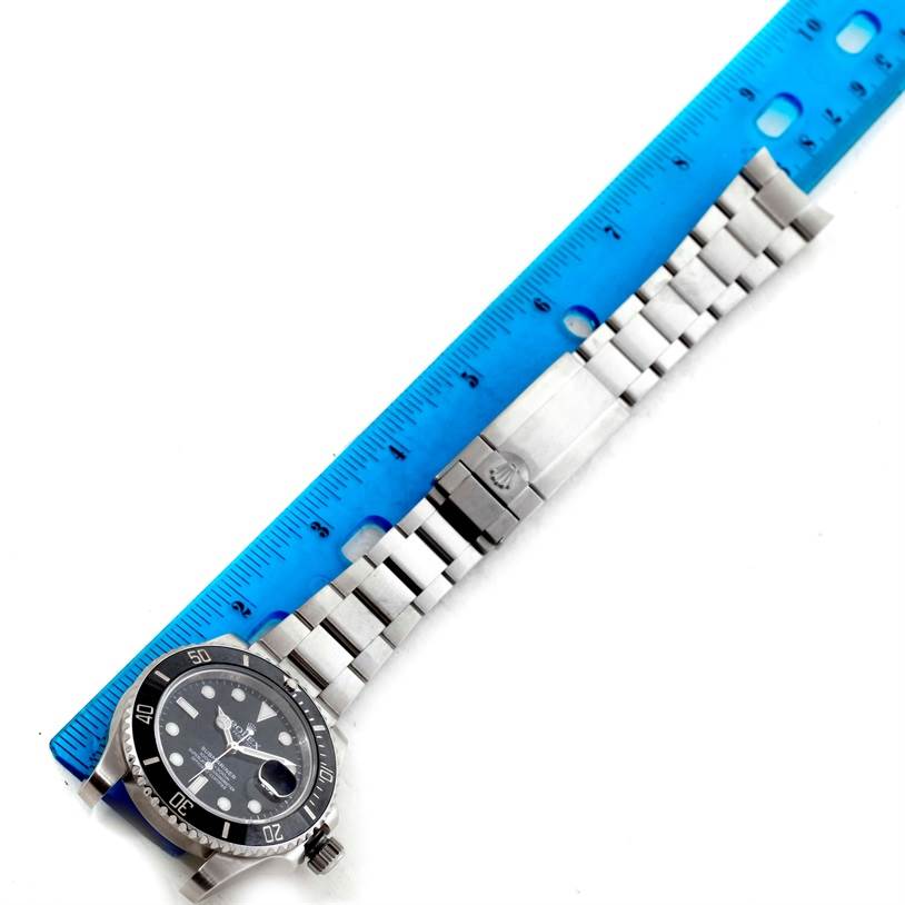 The image shows a Rolex Submariner 116610 Men
s Stainless Steel Black Dial 116610 Men
s Stainless Steel Black Dial watch laid flat beside a ruler, highlighting its full bracelet and clasp.