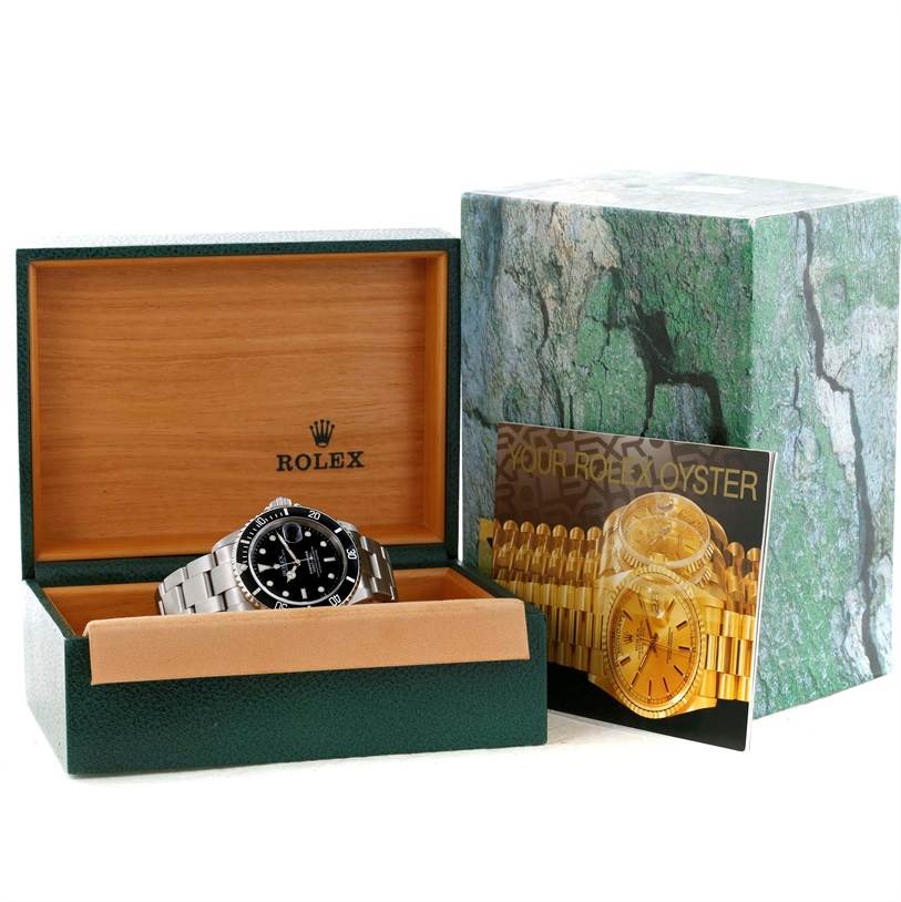 The Rolex Submariner 16610 Men
s Stainless Steel Black Dial 16610 Men
s Stainless Steel Black Dial watch is shown in its open box, along with an instruction booklet beside it.