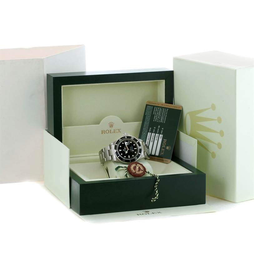The image shows a Rolex Submariner 16610 Men
s Stainless Steel Black Dial 16610 Men
s Stainless Steel Black Dial watch and its box, card, and tags from a front-facing angle.