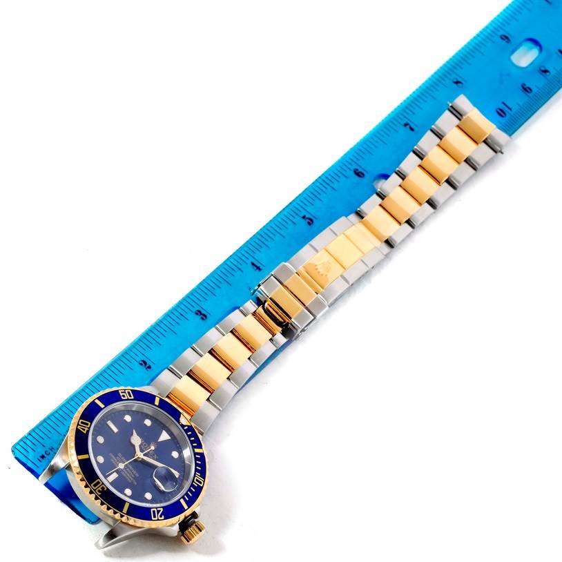 The image shows a Rolex Submariner 16613 Men
s Steel and Gold (two tone) Blue Dial 16613 Men
s Steel and Gold (two tone) Blue Dial watch laid flat with a measuring ruler, displaying the face, bezel, and bracelet.