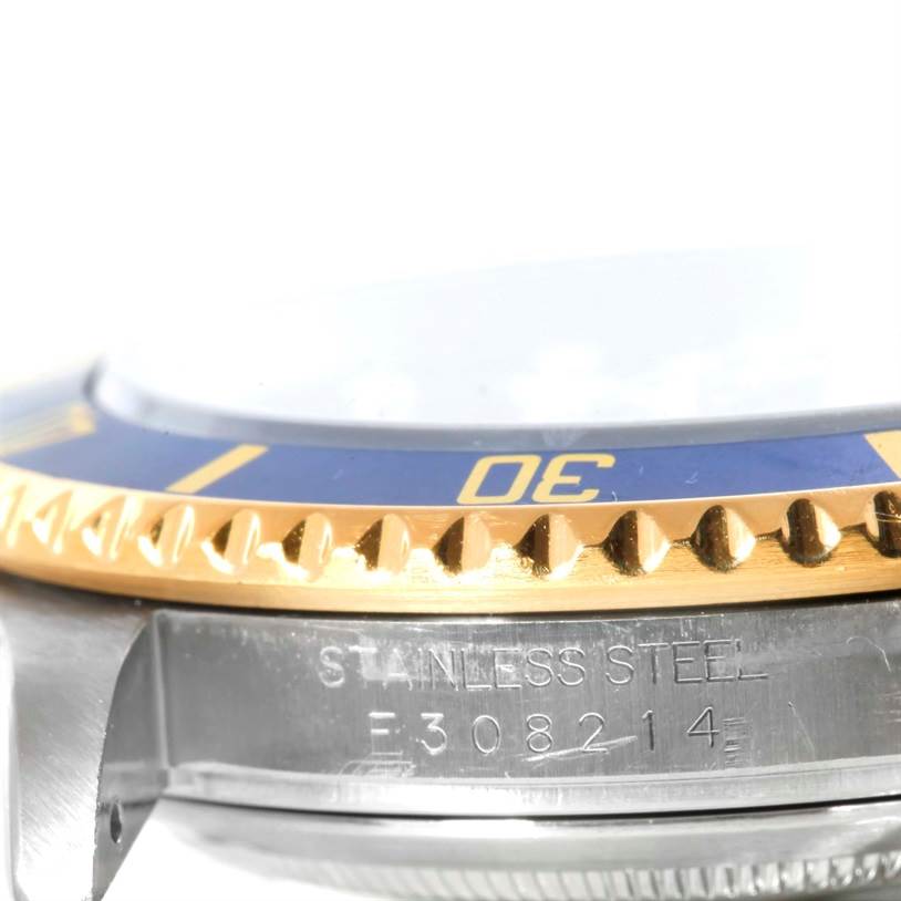 This image shows a close-up of the Rolex Submariner 16613 Men
s Steel and Gold (two tone) Blue Dial 16613 Men
s Steel and Gold (two tone) Blue Dial
s blue and gold bezel and part of its stainless steel case with serial number.