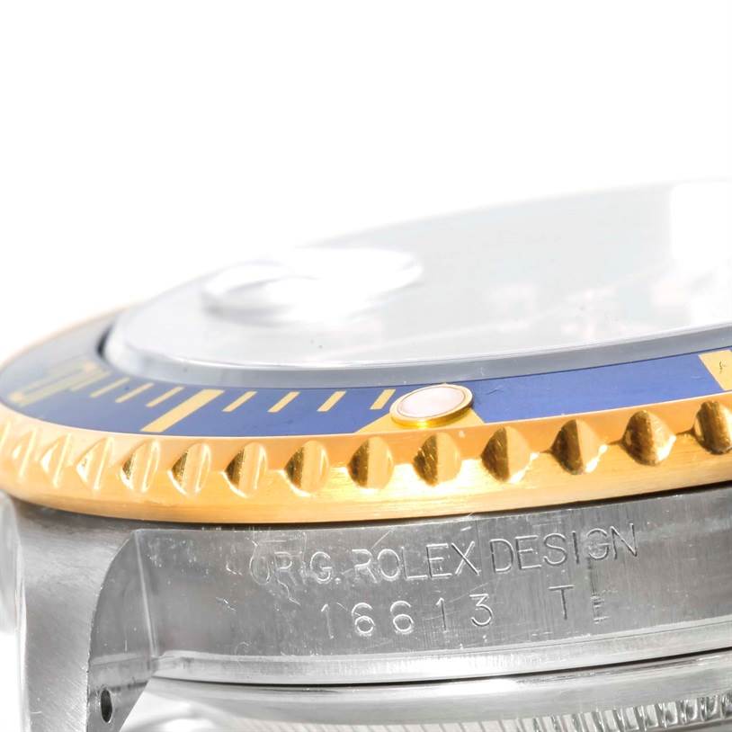 This image shows a close-up angle of a stainless steel and gold bezel with part of the case and engravings of a Rolex Submariner 16613 Men
s Steel and Gold (two tone) Blue Dial 16613 Men
s Steel and Gold (two tone) Blue Dial watch.