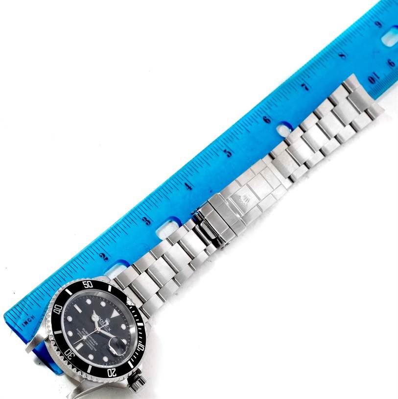 The image shows a Rolex Submariner 16610 Men's Stainless Steel Black Dial 16610 Men's Stainless Steel Black Dial watch laid flat with its bracelet extended alongside a ruler.