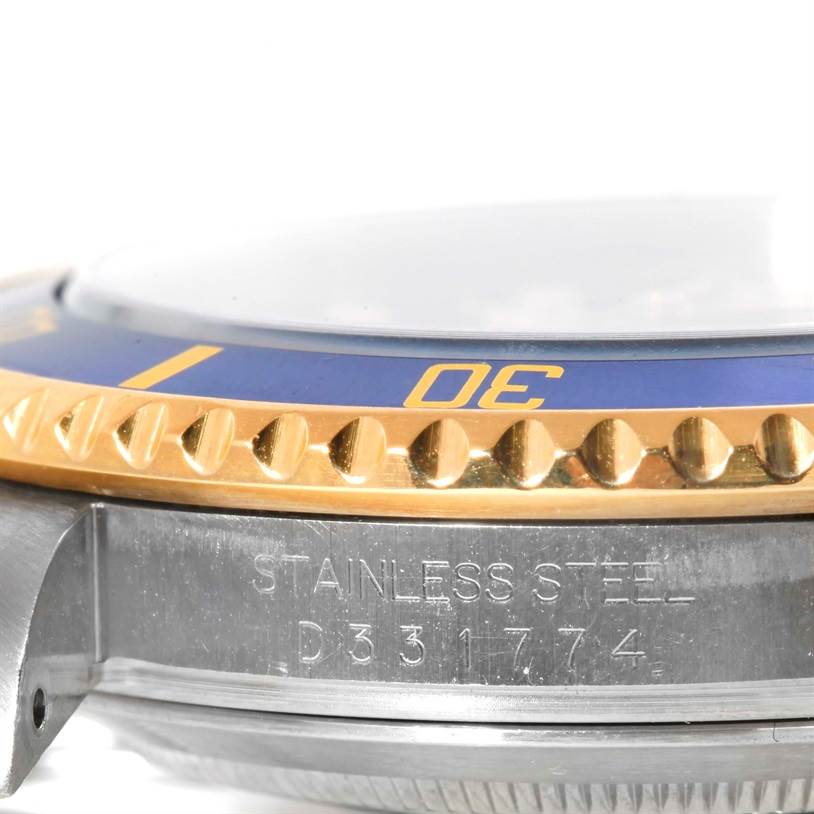 This close-up image of the Rolex Submariner 16613 Men
s Steel and Gold (two tone) Blue Dial 16613 Men
s Steel and Gold (two tone) Blue Dial watch shows the side view of the bezel, the stainless steel case, and part of the serial number.