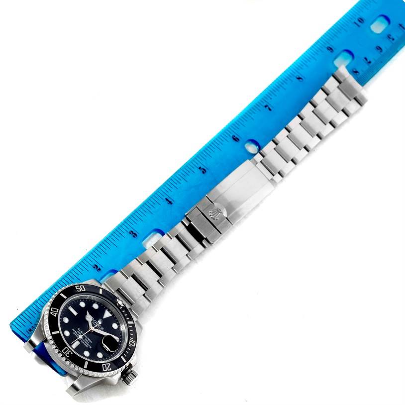 The image shows a flatly laid Rolex Submariner 116610 Men
s Stainless Steel Black Dial 116610 Men
s Stainless Steel Black Dial watch next to a blue ruler, highlighting its bracelet and face.