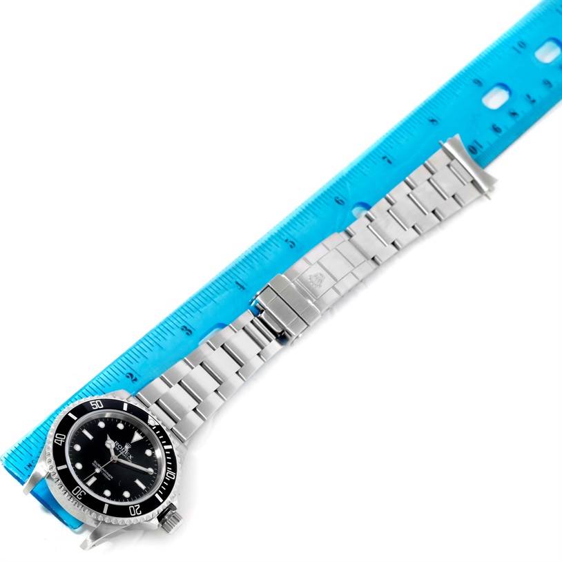 The image shows a Rolex Submariner 14060 Men
s Stainless Steel Black Dial 14060 Men
s Stainless Steel Black Dial watch laid flat next to a blue ruler, displaying the entire watch including the face, bezel, and bracelet.