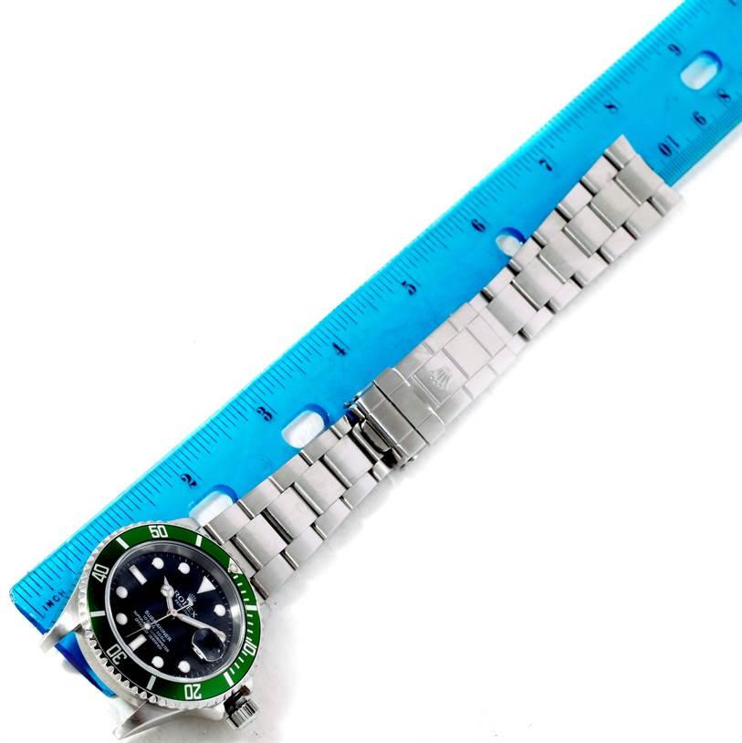 The Rolex Submariner 16610LV Men
s Stainless Steel Black Dial 16610LV Men
s Stainless Steel Black Dial watch is shown flat with its face and band visible, positioned alongside a blue ruler for measurement.