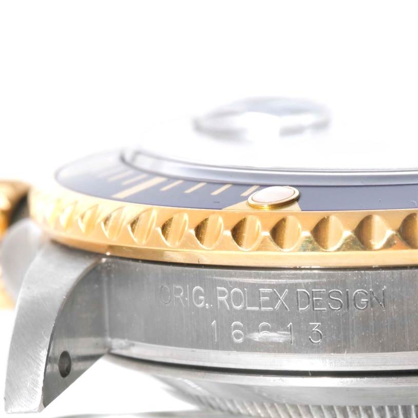The image shows a close-up of the side of the Rolex Submariner 16613 Men
s Steel and Gold (two tone) Blue Dial 16613 Men
s Steel and Gold (two tone) Blue Dial, focusing on the bezel and the model engraving.