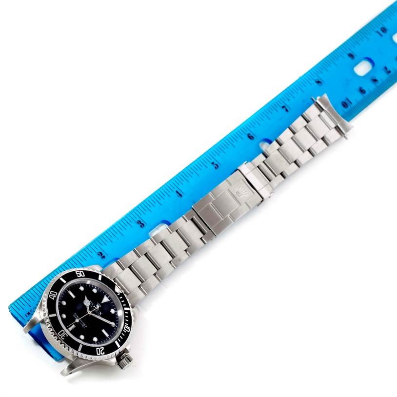 The image shows a top-down view of a Rolex Submariner 14060 Men
s Stainless Steel Black Dial 14060 Men
s Stainless Steel Black Dial watch with its bracelet laid against a ruler for scale.