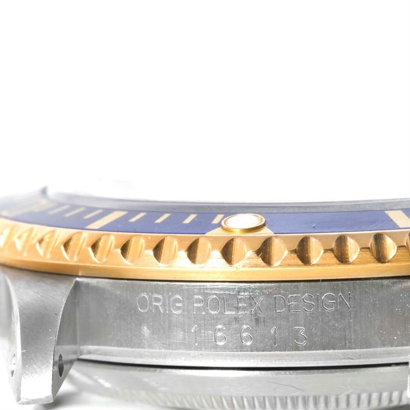 This image shows the side view of a Rolex Submariner 16613 Men's Steel and Gold (two tone) Champagne Dial 16613 Men's Steel and Gold (two tone) Champagne Dial's case and bezel, displaying the model number 16613 and "Orig Rolex Design" inscription.