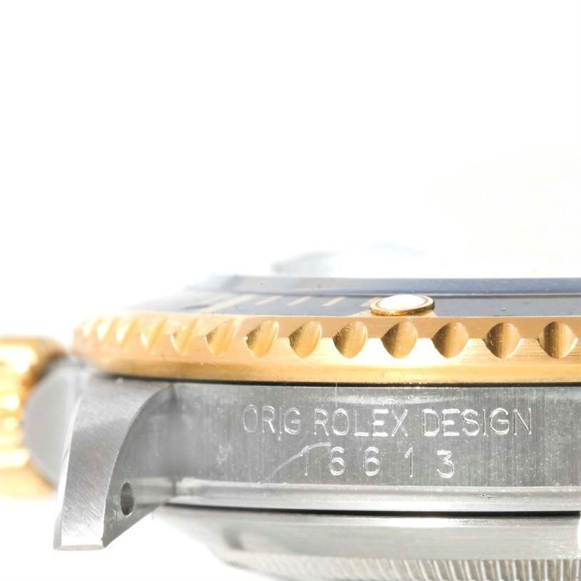 This image shows a close-up side view of the bezel, crown guard, and part of the case of a Rolex Submariner 16613 Men
s Steel and Gold (two tone) Black Dial 16613 Men
s Steel and Gold (two tone) Black Dial watch, featuring the model number engraved.