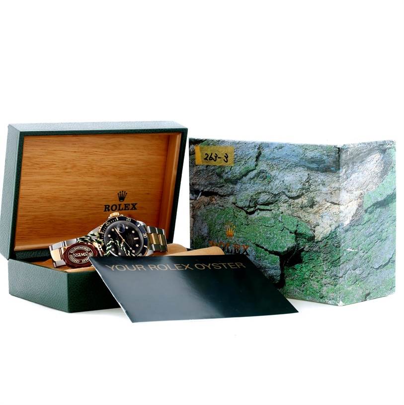 The image shows a Rolex Submariner 16613 Men
s Steel and Gold (two tone) Black Dial 16613 Men
s Steel and Gold (two tone) Black Dial watch displayed in its open box, alongside an outer box and a booklet.