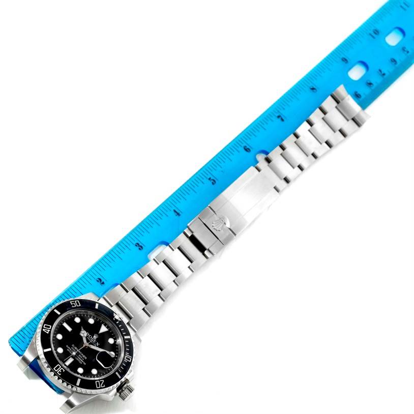 The image shows a Rolex Submariner 116610 Men
s Stainless Steel Black Dial 116610 Men
s Stainless Steel Black Dial watch positioned horizontally with a blue ruler measuring its metal bracelet.