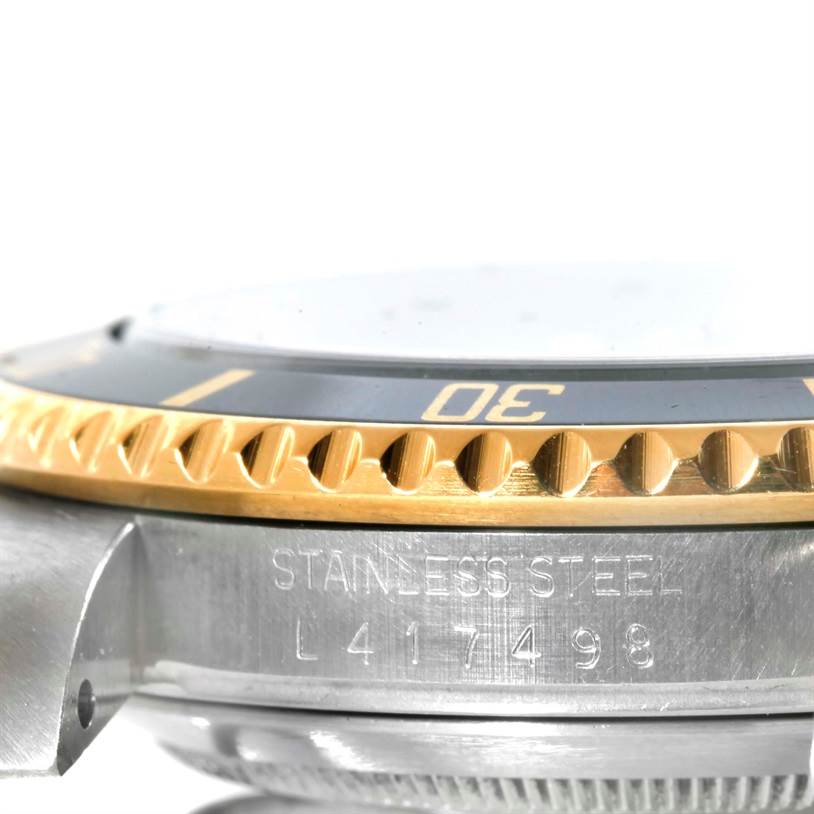 The image shows a close-up side view of the Rolex Submariner 16613 Men's Steel and Gold (two tone) Black Dial 16613 Men's Steel and Gold (two tone) Black Dial watch, highlighting the bezel and part of the casing with the serial number.