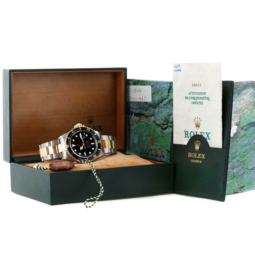 The image shows a Rolex Submariner 16613 Men's Steel and Gold (two tone) Black Dial 16613 Men's Steel and Gold (two tone) Black Dial watch in its open box, along with accompanying documents and accessories.