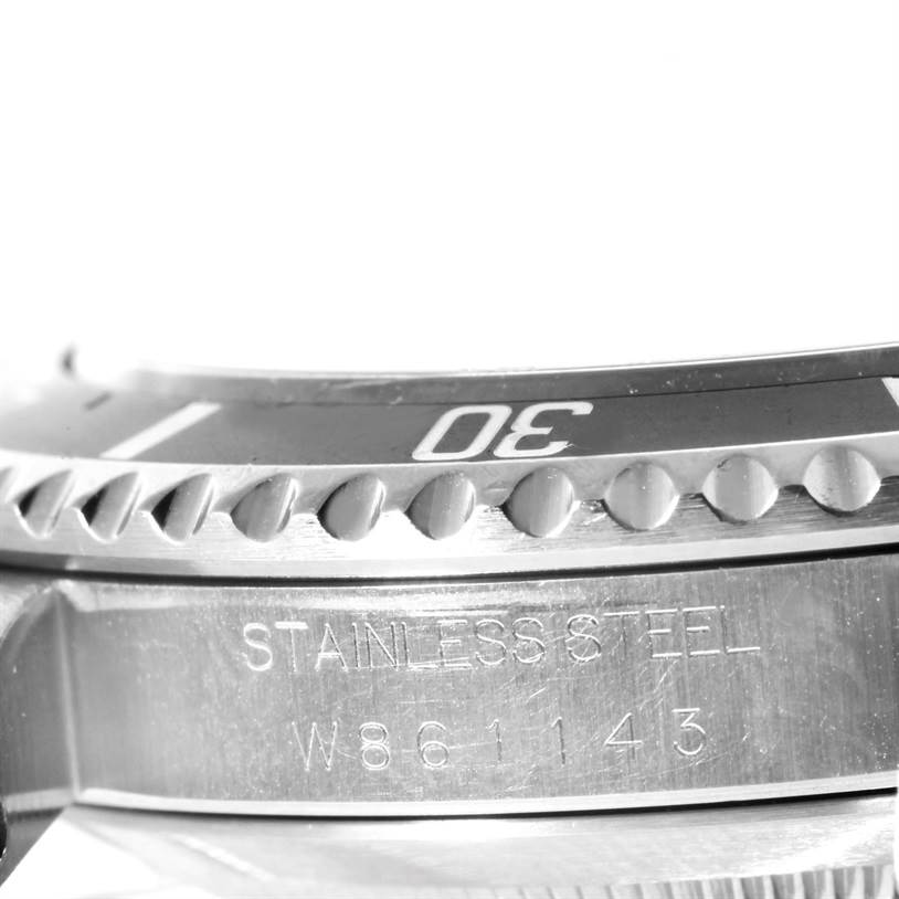 This image shows a close-up side view of the Rolex Submariner 14060 Men
s Stainless Steel Black Dial 14060 Men
s Stainless Steel Black Dial
s bezel and case, highlighting the "STAINLESS STEEL" engraving and part of the serial number.