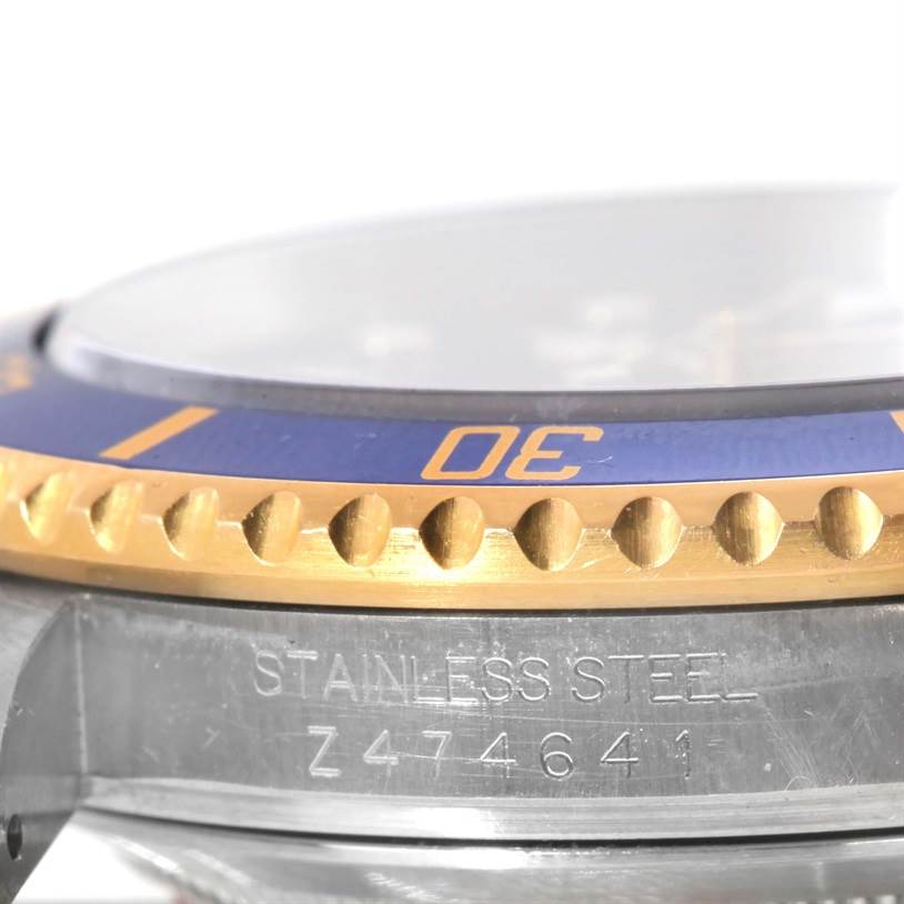 The image shows a close-up of the bezel and part of the case of the Rolex Submariner 16613 Men's Steel and Gold (two tone) Blue Dial 16613 Men's Steel and Gold (two tone) Blue Dial watch, revealing "STAINLESS STEEL" and a serial number.