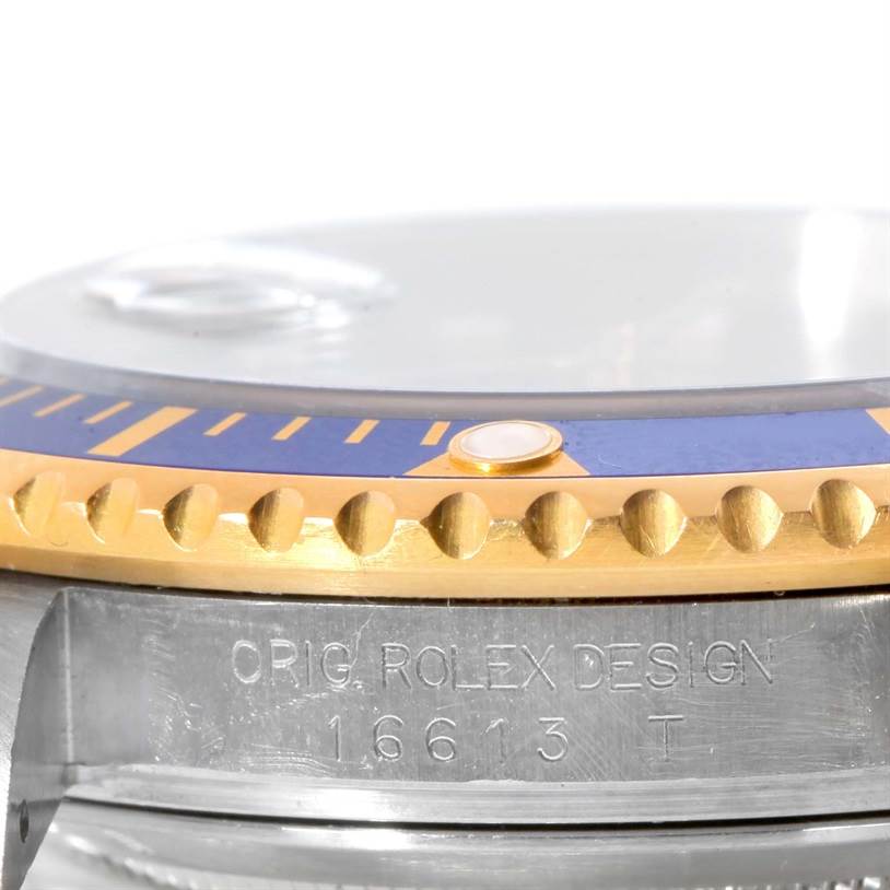 The image shows a close-up side view of a Rolex Submariner 16613 Men's Steel and Gold (two tone) Blue Dial 16613 Men's Steel and Gold (two tone) Blue Dial's bezel and part of the case, highlighting the model number and bezel details.