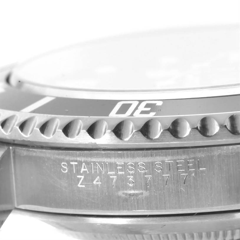This close-up image of a Rolex Submariner 14060 Men
s Stainless Steel Black Dial 14060 Men
s Stainless Steel Black Dial shows its bezel, case edge, and part of the serial number engraving.