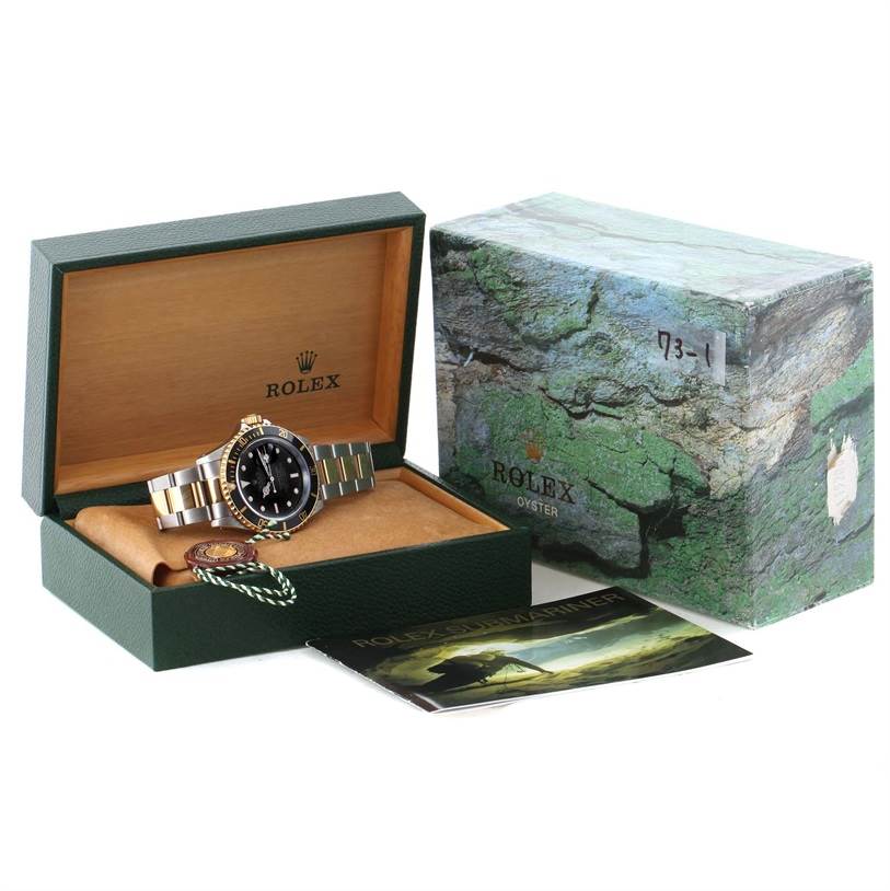 The image shows a Rolex Submariner 16613 Men's Steel and Gold (two tone) Black Dial 16613 Men's Steel and Gold (two tone) Black Dial watch in its box, parts include the watch, tags, and manuals, with outer packaging visible.