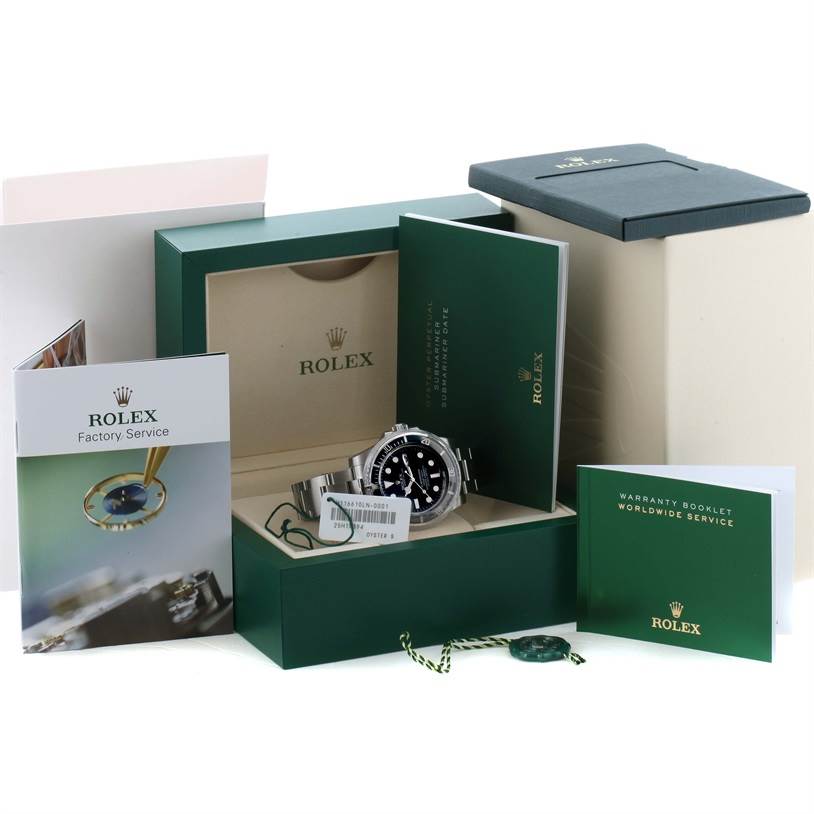 The image shows a Rolex Submariner 116610 Men
s Stainless Steel Black Dial 116610 Men
s Stainless Steel Black Dial watch along with its box, warranty booklet, factory service book, and tags, all from a slightly elevated angle.