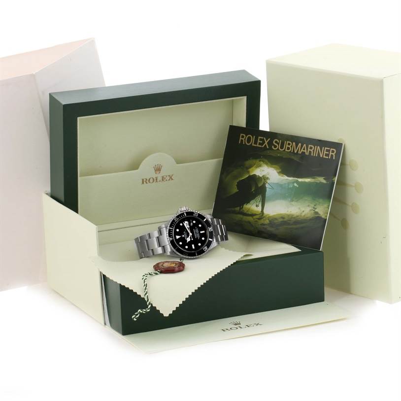 The image shows a Rolex Submariner 16610 Men
s Stainless Steel Black Dial 16610 Men
s Stainless Steel Black Dial watch at an angle with its box, booklet, and tag.