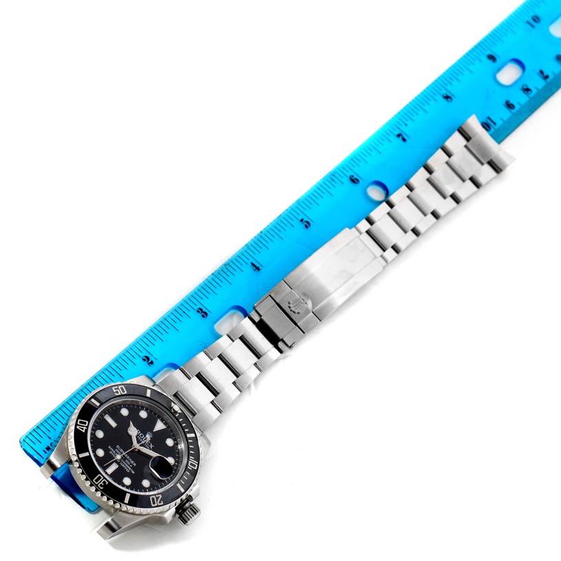 The Rolex Submariner 116610LN Men
s Stainless Steel Black Dial 116610LN Men
s Stainless Steel Black Dial watch is shown from above, including the watch face, bezel, bracelet, and clasp next to a blue ruler.