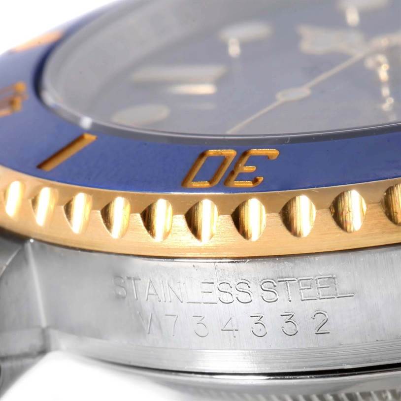 This image shows a close-up of the bezel, part of the dial, and the case with the serial number of the Rolex Submariner 116613 Men's Steel and Gold (two tone) Blue Dial 116613 Men's Steel and Gold (two tone) Blue Dial watch.