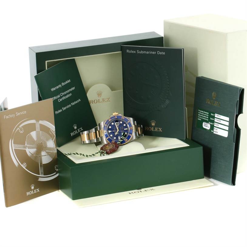 The image shows a Rolex Submariner 116613 Men's Steel and Gold (two tone) Blue Dial 116613 Men's Steel and Gold (two tone) Blue Dial watch with a blue dial, placed inside its green display box, accompanied by booklets and warranty cards.