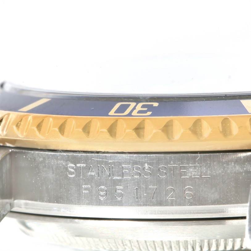 The image shows a close-up side view of the bezel and case side of a Rolex Submariner 16613 Men's Steel and Gold (two tone) Blue Dial 16613 Men's Steel and Gold (two tone) Blue Dial, including the serial number and "Stainless Steel" engraving.