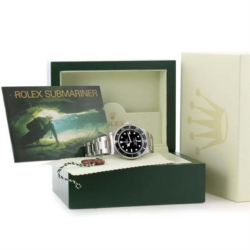 The image shows a Rolex Submariner 14060 Men
s Stainless Steel Black Dial 14060 Men
s Stainless Steel Black Dial watch in its open box, accompanied by its manual and tag, viewed from a front angle.