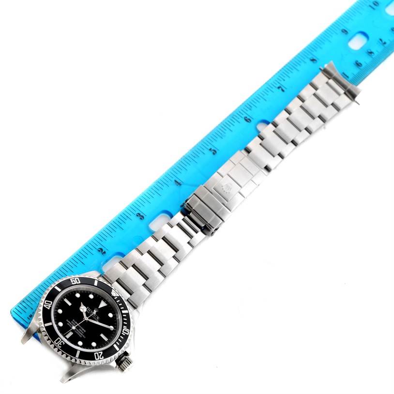 The image shows a top-down view of a Rolex Submariner 14060 Men
s Stainless Steel Black Dial 14060 Men
s Stainless Steel Black Dial watch alongside a blue ruler for scale, highlighting the full length of the bracelet and face.