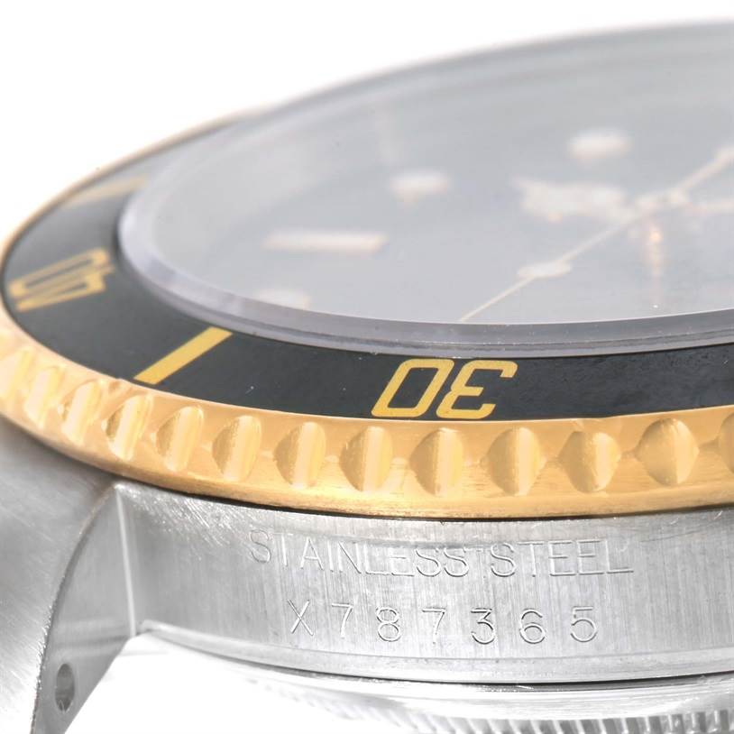 The image shows a close-up side view of the Rolex Submariner 16613 Men's Steel and Gold (two tone) Black Dial 16613 Men's Steel and Gold (two tone) Black Dial watch, highlighting the bezel, crystal, and part of the case with engraved details.