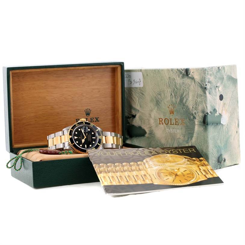 The image shows a Rolex Submariner 16613 Men's Steel and Gold (two tone) Black Dial 16613 Men's Steel and Gold (two tone) Black Dial watch at a front angle inside its open box with accompanying booklets and packaging.