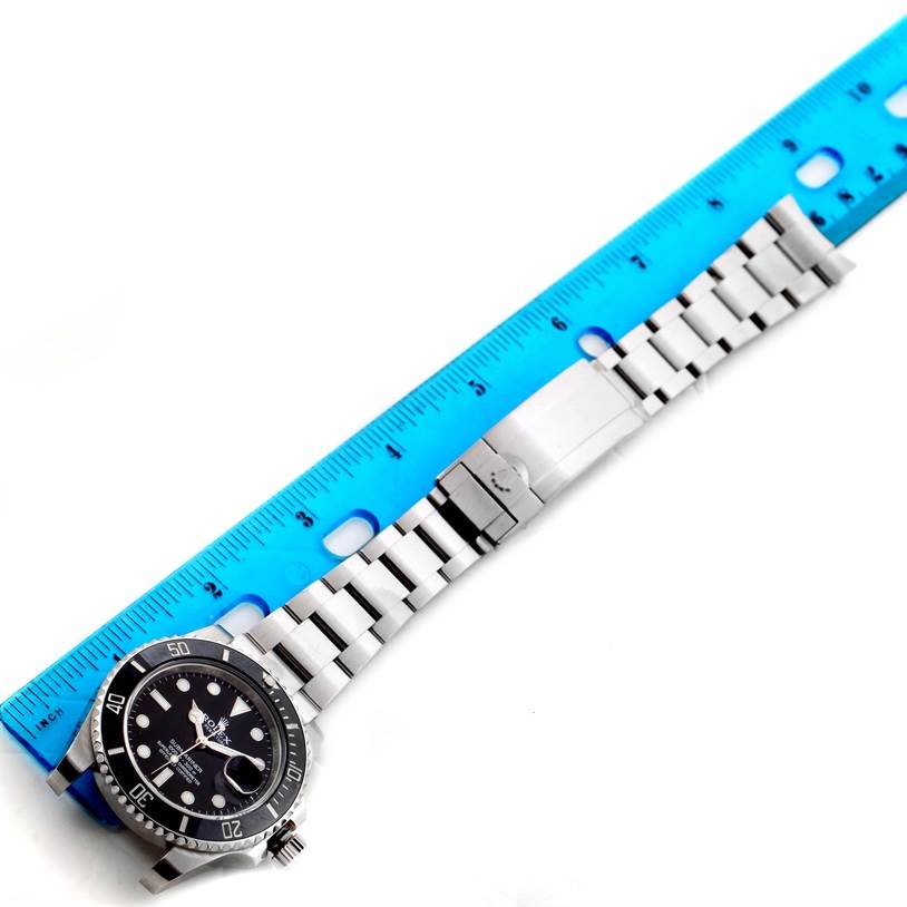 The image shows a top-down view of a Rolex Submariner 116610LN Men
s Stainless Steel Black Dial 116610LN Men
s Stainless Steel Black Dial watch with a blue ruler aligned next to its bracelet.