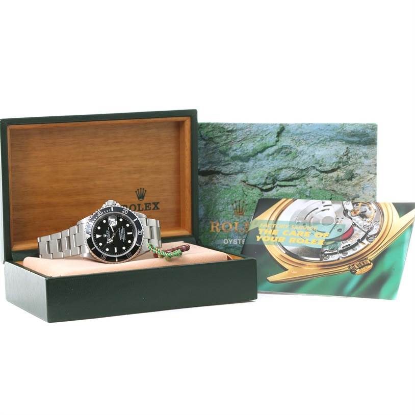 The Rolex Submariner 16610 Men
s Stainless Steel Black Dial 16610 Men
s Stainless Steel Black Dial watch is displayed inside its box, with accompanying booklets and packaging in the background.